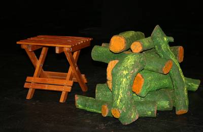 un detalle de la escenografía con la mesita de madera y un montón de troncos